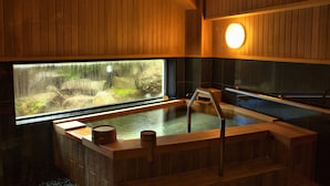 Una sauna de madera con un ventanal grande, un banco de madera y una pequeña mesa de madera.