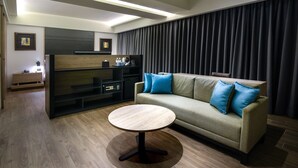 Een moderne woonkamer met een ronde houten tafel, een bank met blauwe kussens en een donkere gordijnenachtergrond.