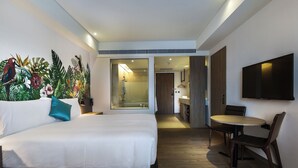 Een moderne hotelkamer met een groot bed, een eettafel met stoelen, een televisie en een douche.