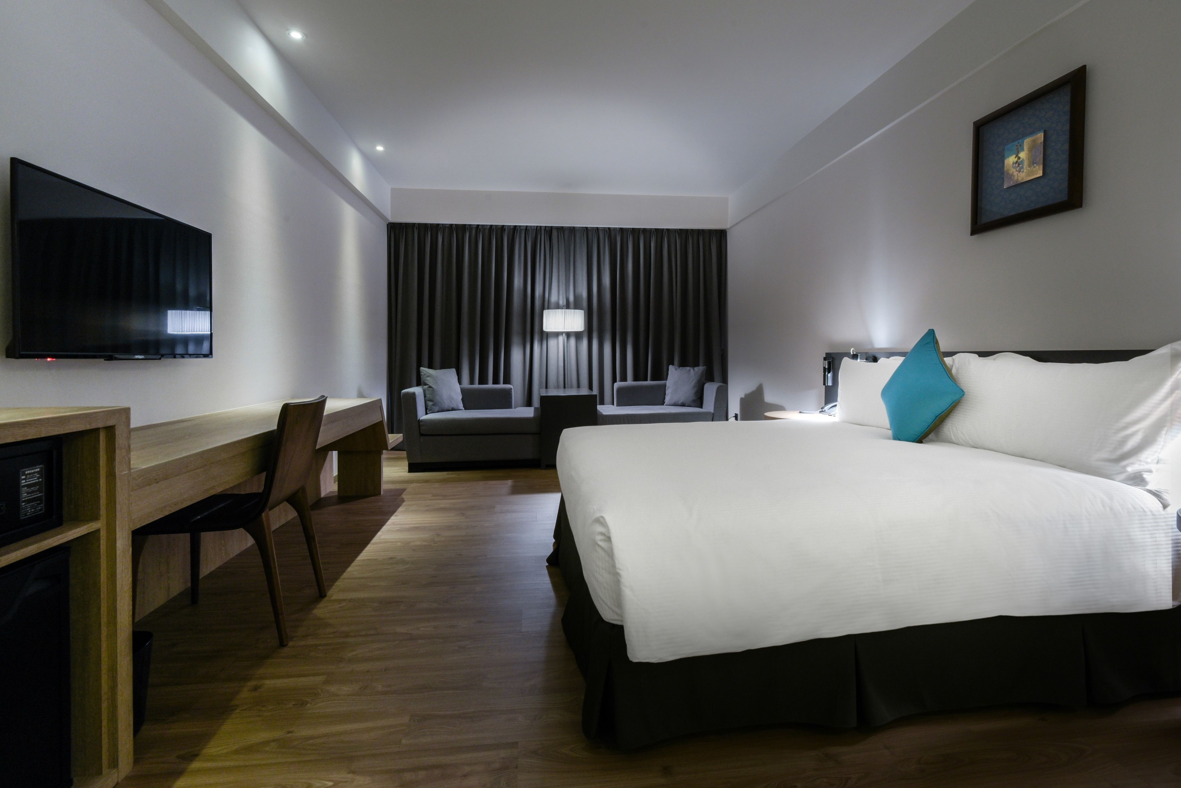 A hotel room with a bed, a desk, a TV, and a couch.