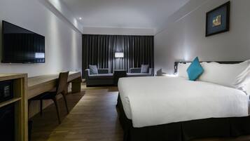 A hotel room with a bed, a desk, a TV, and a couch.