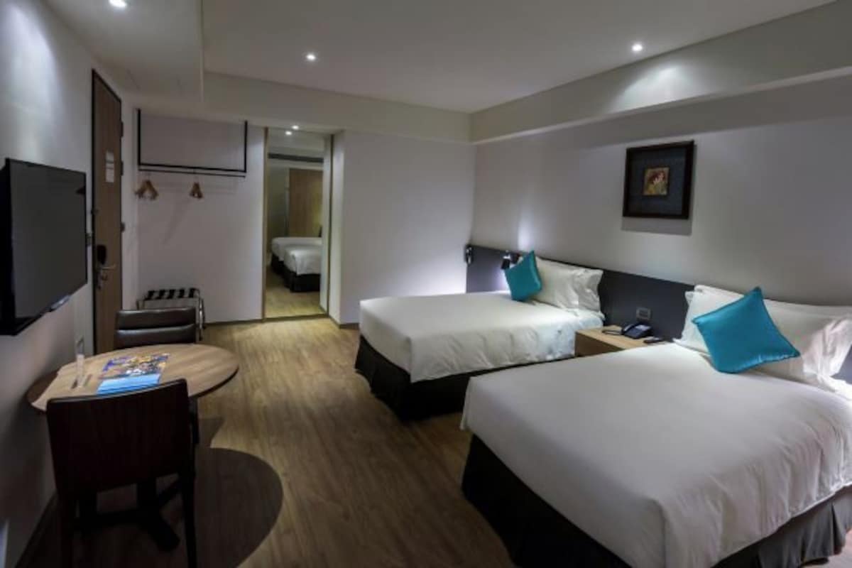 Une chambre d’hôtel avec deux lits, un bureau, une chaise et un téléviseur.