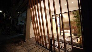 Vista nocturna de un edificio con una puerta de madera y un interior iluminado.