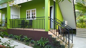 Ein grünes Gebäude mit Balkon, Treppe und Blumentöpfen.