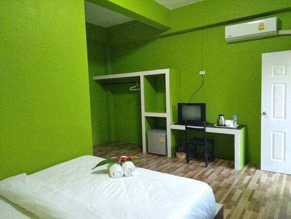 Habitación de hotel con cama, escritorio con televisor, armario y equipo de aire acondicionado.