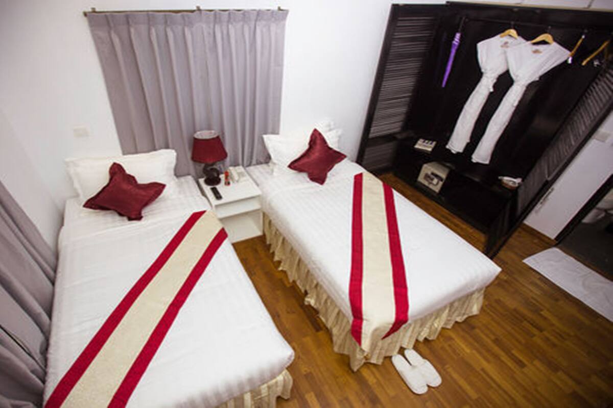 A hotel room with two beds, a vanity with a mirror, a wardrobe, and a shoe rack.