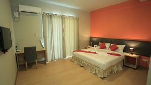 Ein Schlafzimmer mit einem Bett, einem Schreibtisch, einem Stuhl, einem Fernseher und einem Nachttisch mit einer Lampe.