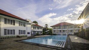 A swimming pool area with a building on one side and a stone wall on the other. - Griya Sintesa Muara Enim (Muara Enim)