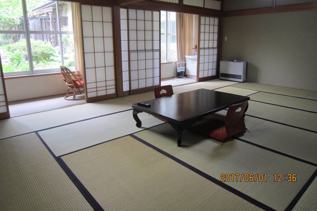 Una habitación japonesa tradicional con suelo de tatami, una mesa baja y puertas correderas.