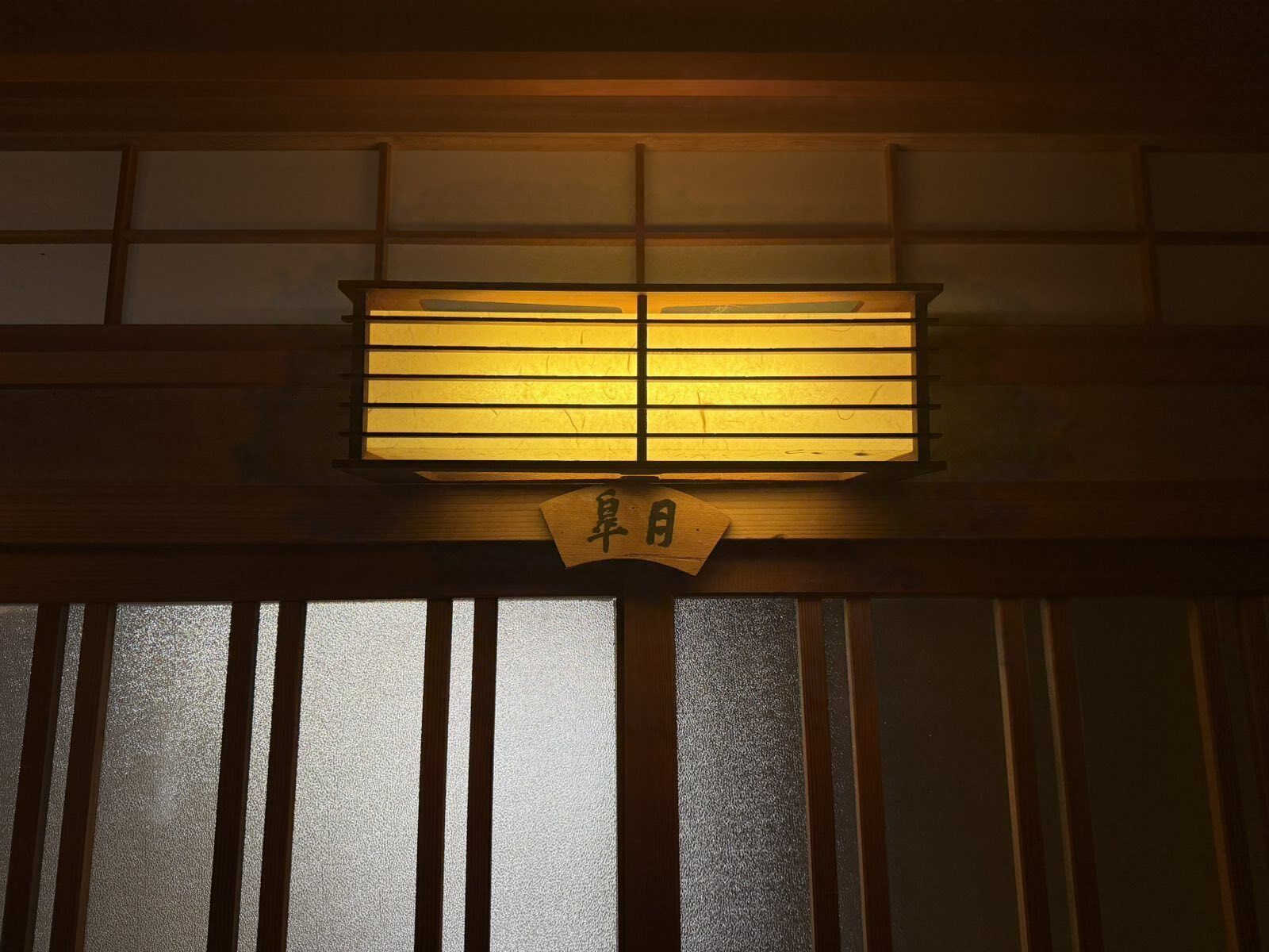 Een traditioneel Japans shoji-scherm met een houten bord erboven.