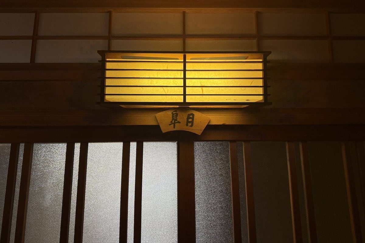 Un paravent japonais traditionnel de type shoji, surmonté d’une enseigne en bois.