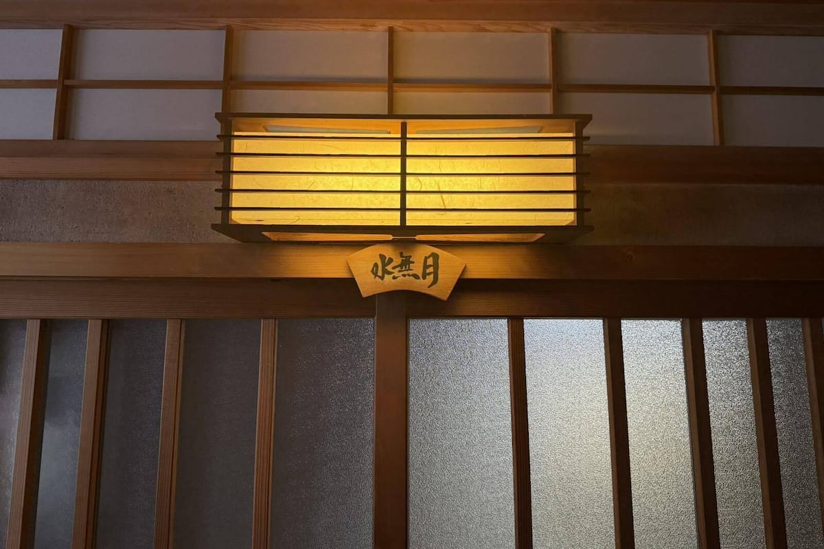 Une pièce de style japonais traditionnel, dotée d’une porte coulissante et d’une enseigne en bois portant des caractères japonais.