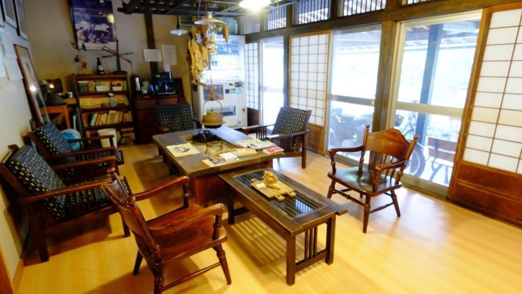 A traditional Japanese room with tatami flooring, a low table, wooden chairs, and a sliding door.