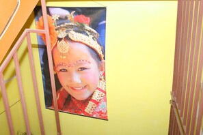 Eine gelbe Wand mit einem gerahmten Bild einer Person in traditioneller Kleidung.