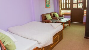 A room with a bed, a sofa, and a window with curtains. - Swastik Guest House (Bhaktapur)
