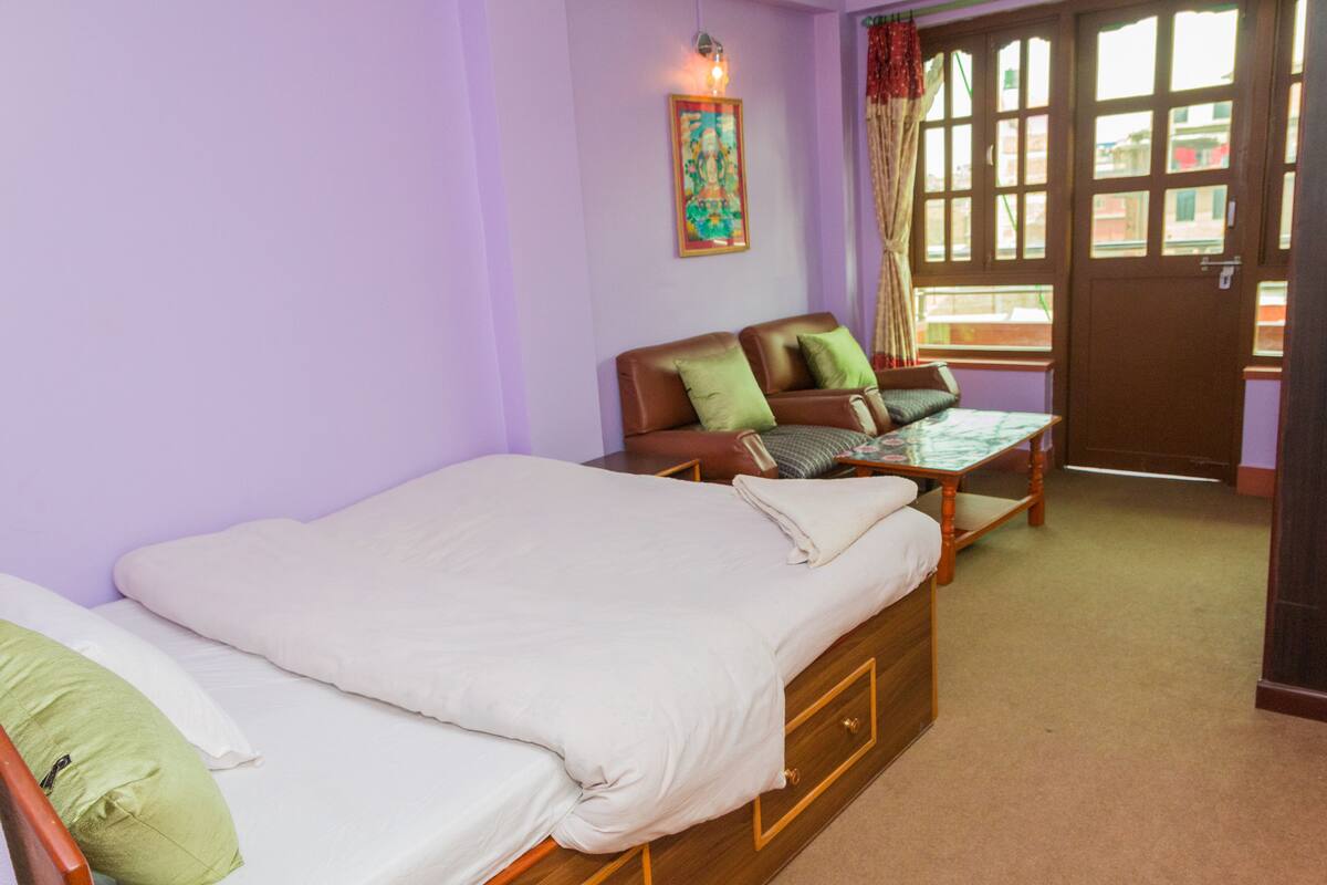 A room with a bed, a sofa, and a window with curtains.