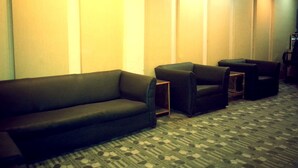 A room with a dark-colored sofa and two armchairs, a patterned carpet, and a wall-mounted heater. - Swastik Guest House (Bhaktapur)