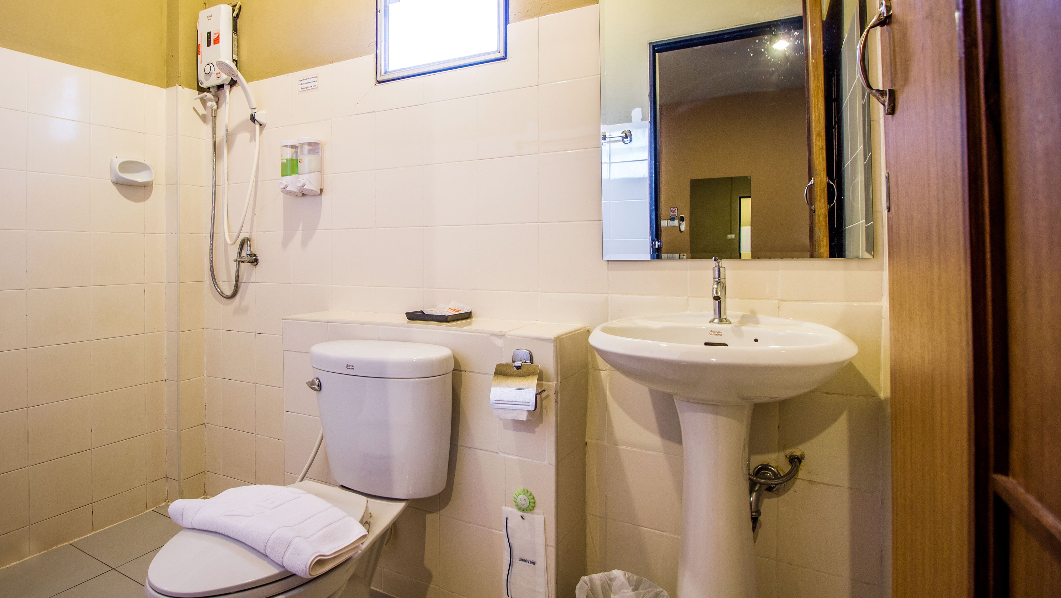 A small, clean bathroom with a toilet, sink, and mirror.