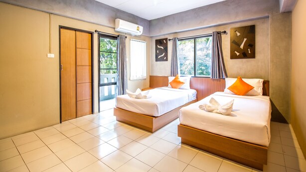 A hotel room with two beds, a sliding door, an air conditioning unit, and a view of greenery outside. - B2 Santitham (Wat Jed Yod) Boutique & Budget Hotel (Chiang Mai)