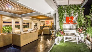 A modern interior with wicker furniture, a reception desk, and a wall with a B2 sign. - B2 Santitham (Wat Jed Yod) Boutique & Budget Hotel (Chiang Mai)