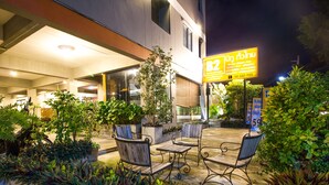 An outdoor seating area with tables and chairs, surrounded by potted plants and greenery. - B2 Santitham (Wat Jed Yod) Boutique & Budget Hotel (Chiang Mai)