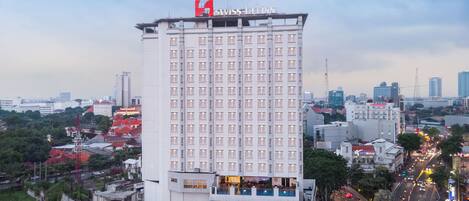 A high-rise hotel with a prominent Swiss logo, multiple floors, and a rooftop pool.