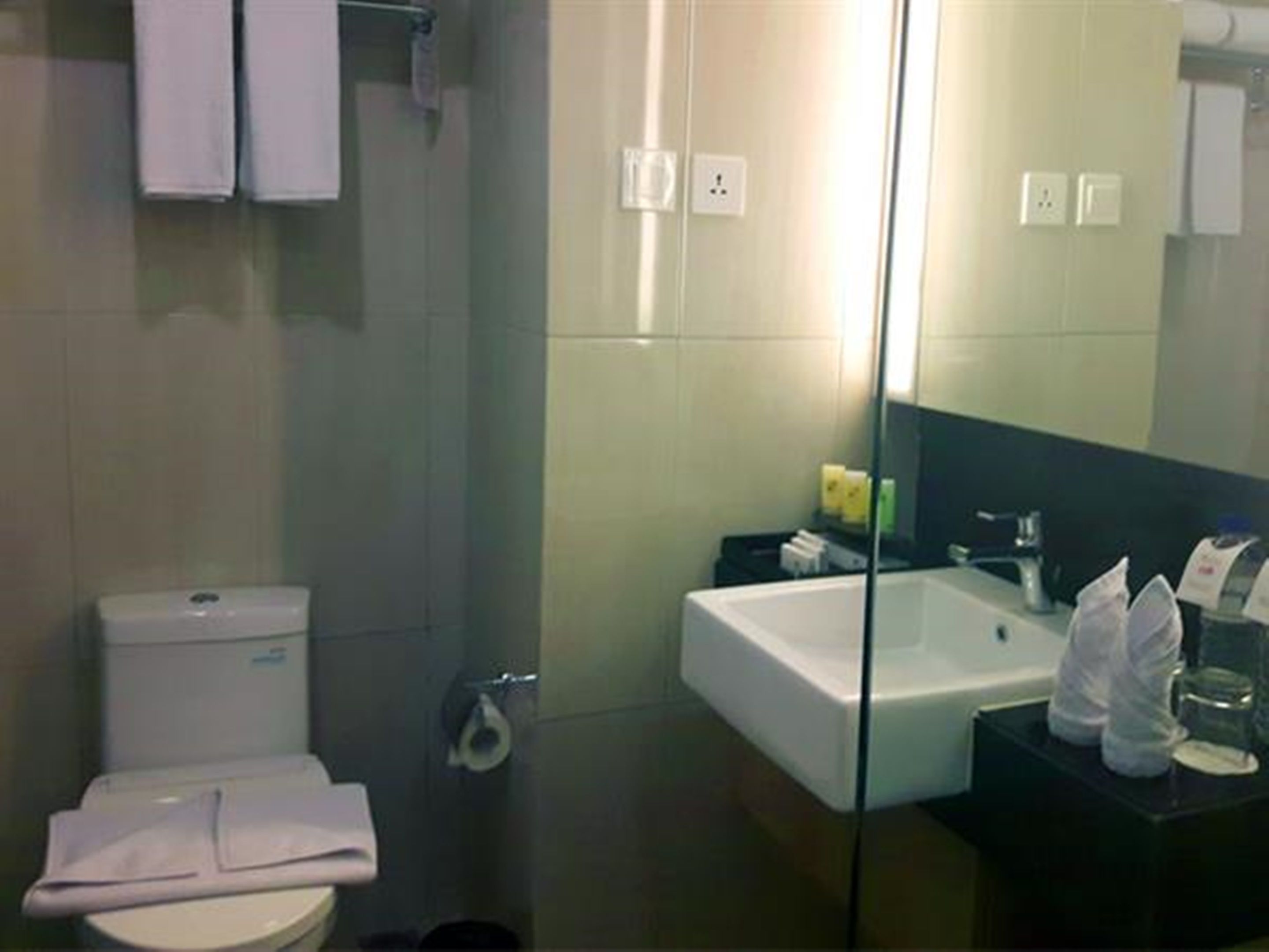 Un baño moderno con inodoro, lavabo y bañera. Hay toallas y artículos de aseo en la encimera.