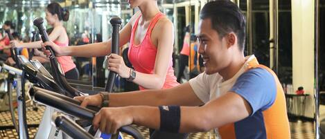 A gym with stationary bikes, mirrors, and a checkered floor.