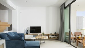 Un saló modern amb un sofà blau, una televisió de pantalla plana, una taula de centre i una zona de menjador amb cadires de fusta.