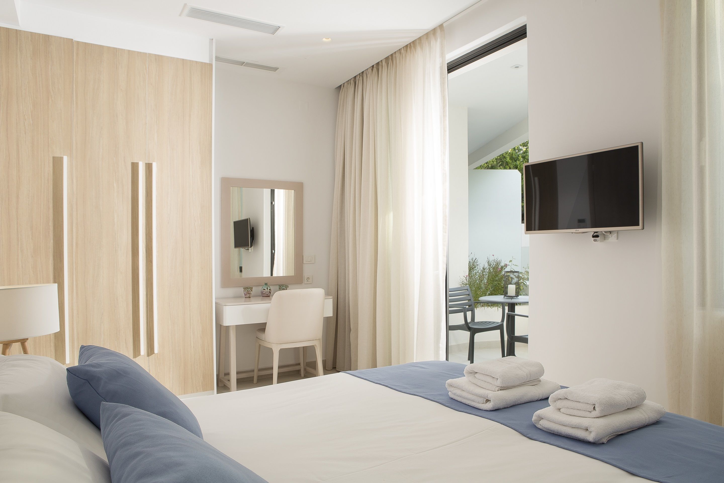 Una habitación de hotel moderna con cama, escritorio, silla y televisor.