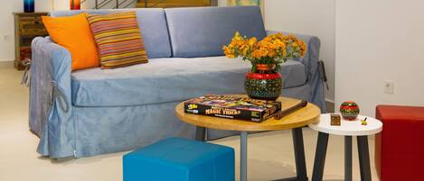 A living room with a sofa, a coffee table, and a red ottoman. There is a book titled "Marvin's Amazing Magic Tricks" on the coffee table.