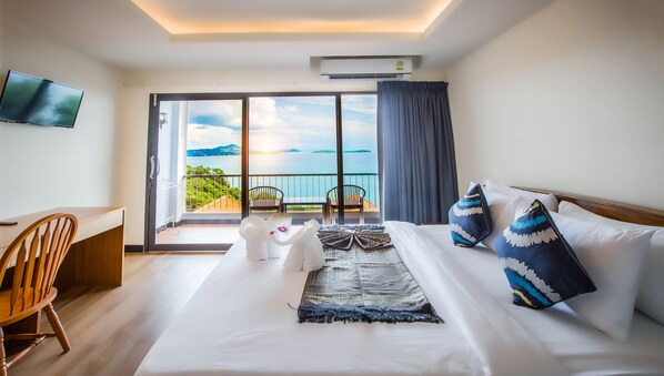 A hotel room with a bed, a desk, a chair, and a balcony with a view of the sea. - Samui Bayview Resort & Spa (Koh Samui)