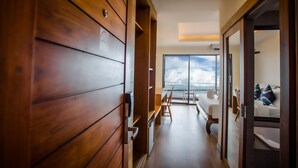A hotel corridor with wooden paneling, a bed, a desk, and a view of the sky through large windows. - Samui Bayview Resort & Spa (Koh Samui)