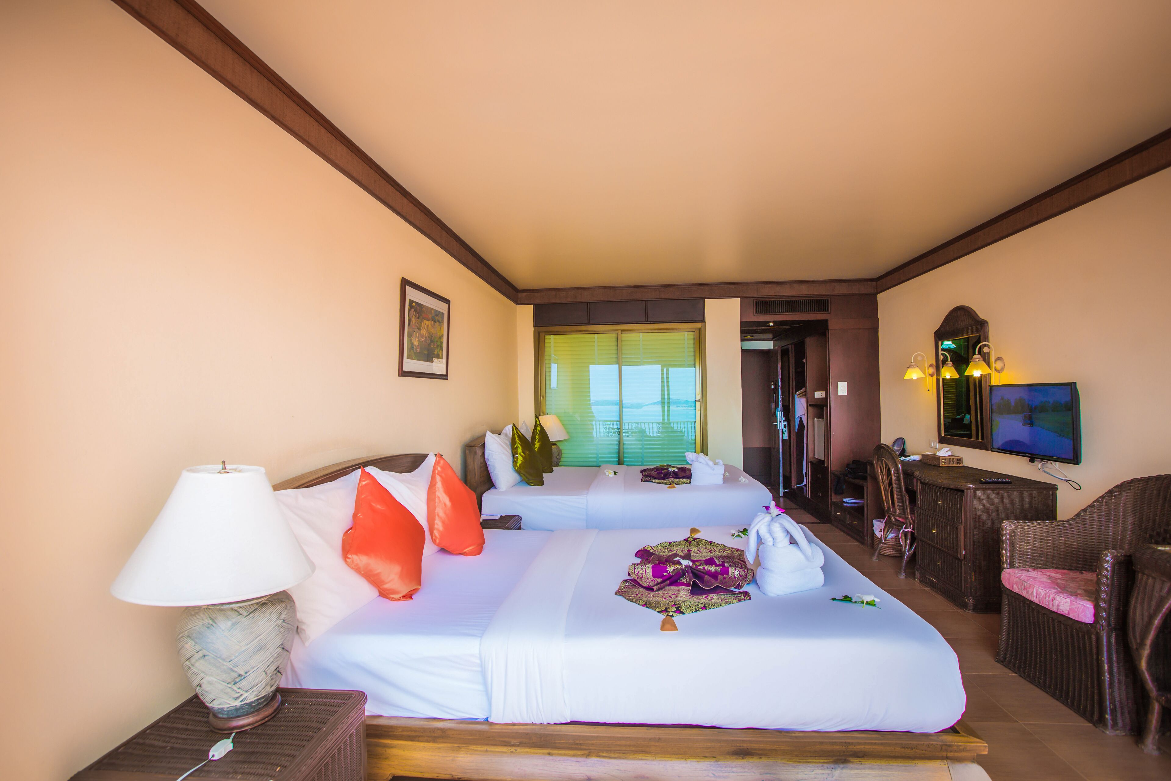 A hotel room with two beds, a television, a desk, and a chair.