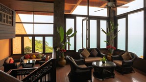 A spacious room with large windows, wicker furniture, and a view of the ocean. - Samui Bayview Resort & Spa (Koh Samui)
