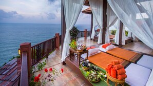 A serene balcony with a view of the sea, a bed with orange towels, and a table with tea and snacks. - Samui Bayview Resort & Spa (Koh Samui)