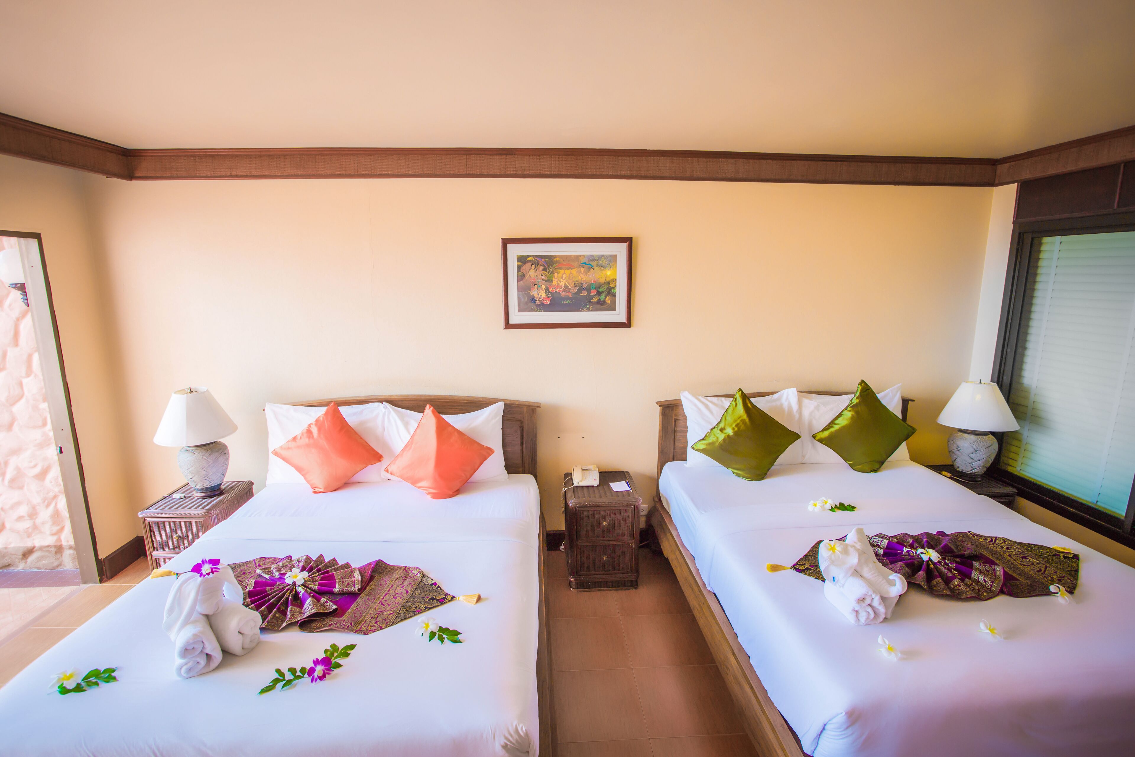 A hotel room with two beds, each with a pillow, a nightstand with a lamp, and a small table with a phone.