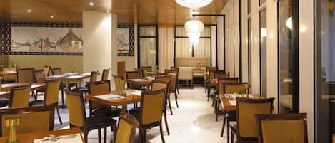 Un restaurant doté de plusieurs tables et chaises, d’un lustre et d’une fresque murale.