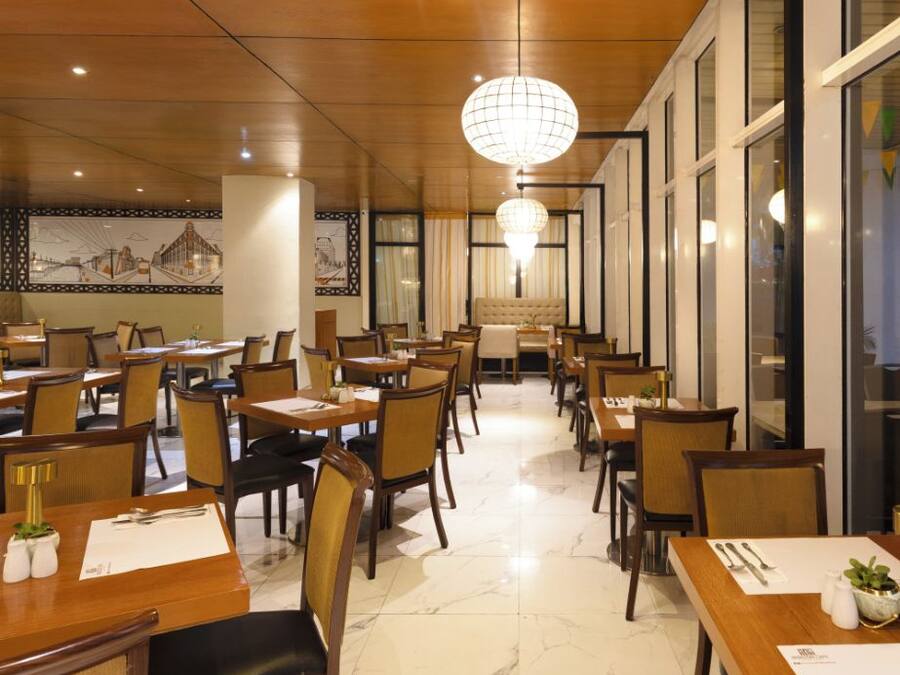 Een restaurant met meerdere eettafels en stoelen, een kroonluchter en een muurschildering.
