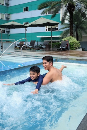 A swimming pool with lounge chairs and umbrellas in the background.