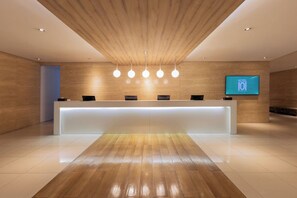 A hotel reception area with a wooden ceiling, a reception desk, and a television screen displaying the hotel name. - Hotel 101 - Manila (Pasay)