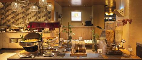 Un montaje tipo buffet con diversos alimentos y una máquina de café.