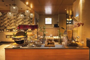 A buffet setup with various food items and a coffee machine.