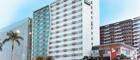 Um hotel com vários andares, varandas e uma placa bem visível.