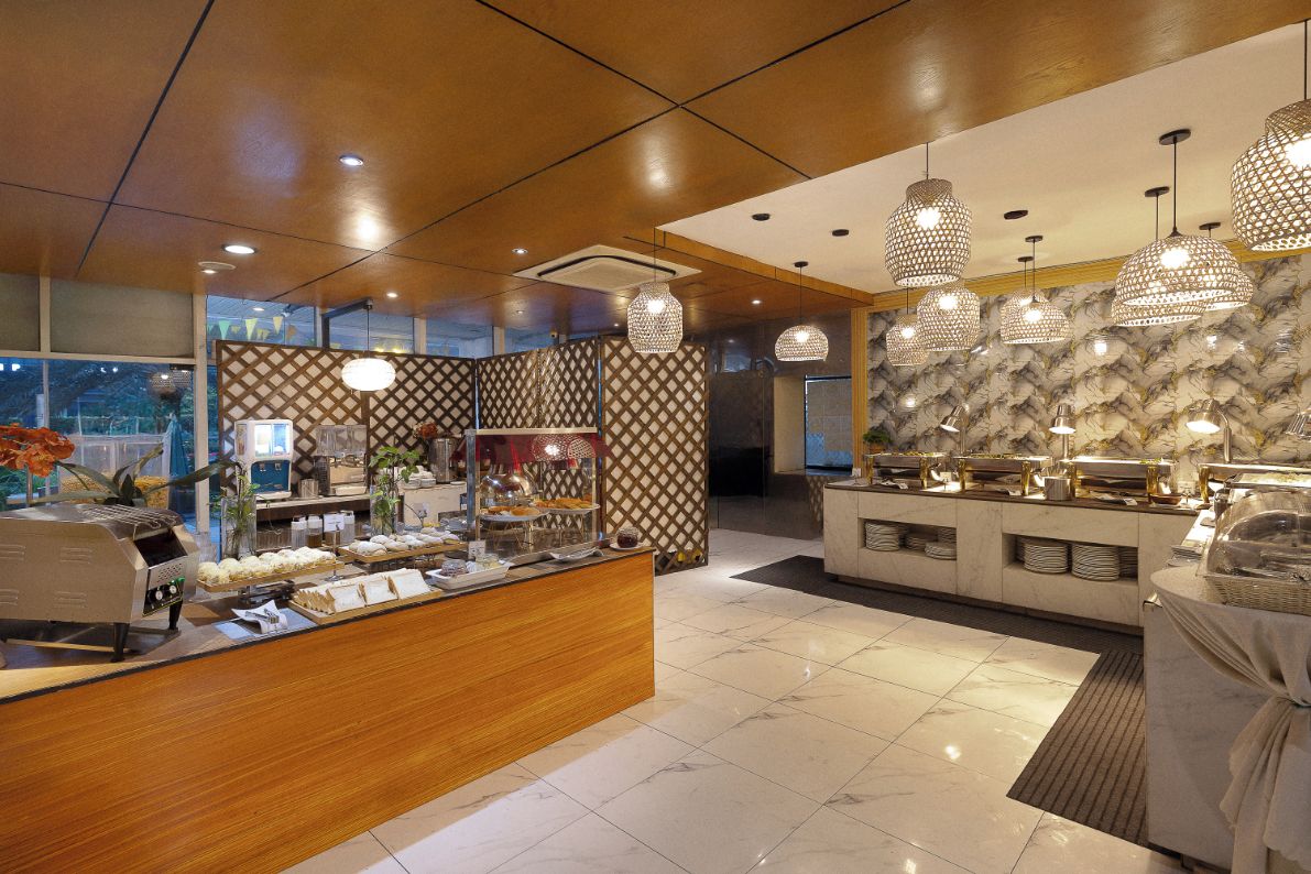 Vestíbulo de hotel con área de bufé, mostrador de recepción y pared con diseño.