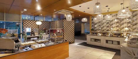 A hotel lobby with a buffet area, a reception desk, and a patterned wall.