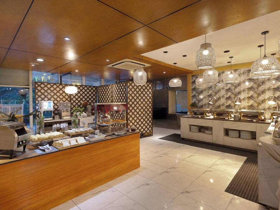 Um saguão de hotel com área de buffet, balcão de recepção e parede com padrão.