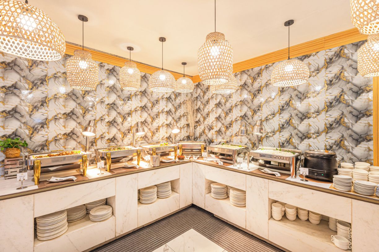 A buffet area with marble walls, multiple serving stations, and hanging pendant lights.