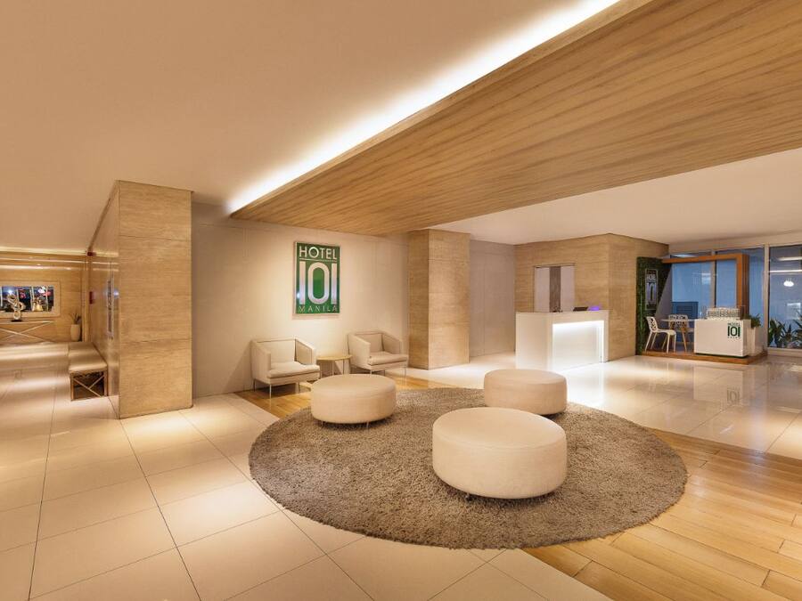 A modern hotel lobby with a reception desk, seating area, and a large sign indicating the hotel name.