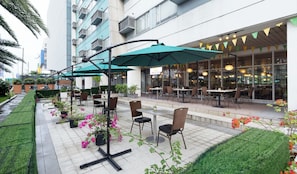 An outdoor patio area with tables and chairs, surrounded by greenery and potted plants. - Hotel 101 - Manila (Pasay)
